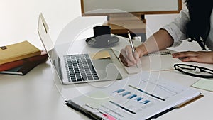 Attractive woman writing in notepad while watching webinar on laptop