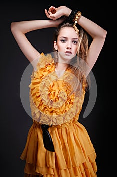 Attractive woman in yellow dress with hands above her head