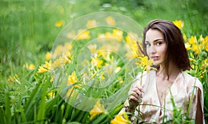 Attractive woman in yellow flowers day-lily field