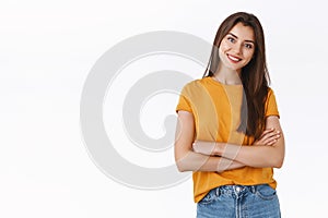 Attractive woman in yellow t-shirt cross hands over chest with self-assured, pleased expression, tilt head and smiling