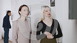 Attractive women in an art gallery at an exhibition of a contemporary artist. Visitors discuss art.