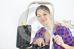 attractive workwoman with toolbox near ladde