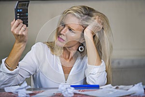 attractive worried and desperate blond woman calculating domestic money expenses doing paperwork and bank bills accounting