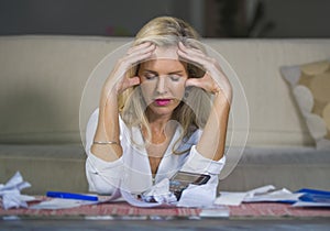 attractive worried and desperate blond woman calculating domestic money expenses doing paperwork and bank bills accounting