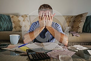 Attractive worried stressed man at home calculating month tax expenses with calculator accounting payments doing bank paperwork in