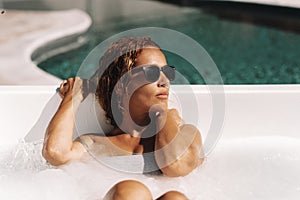 Attractive young adult woman enjoy hydromassage tube and sunny day of summer vacation alone having relax and body care. Luxury