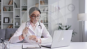 Attractive young African American female doctor wearing glasses is making an online video call consulting a patient on a