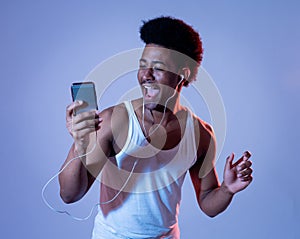 Attractive young african american man with headphones listening to music on mobile in disco light
