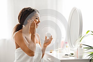 Attractive Young African American Woman Applying Nourishing Cream On Face