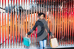 Attractive young African-American woman shopping - shopping bags, outdoors, street view, suitable for holiday shopping themes,