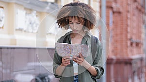 Attractive young African American woman traveling and exploring beautiful sightseeing holding map of city on hands