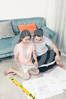 Attractive young asian adult couple looking at house plans.