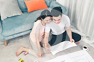 Attractive young asian adult couple looking at house plans.