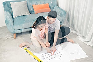 Attractive young asian adult couple looking at house plans.