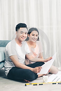 Attractive young asian adult couple looking at house plans.