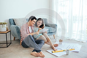 Attractive young asian adult couple looking at house plans.