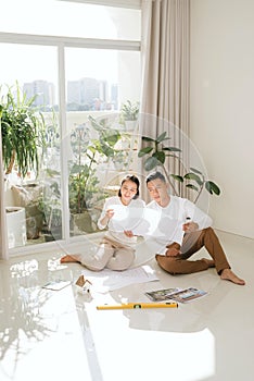 Attractive young asian adult couple looking at house plans