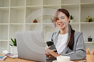 Attractive young asian businesswoman using laptop computer and smartphone