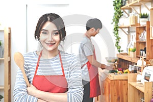 Attractive young asian couple wearing casual orange apron cooking meal in wooden kitchen at home or apartment. Young asian student