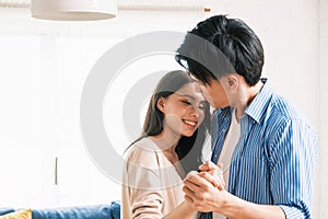 Attractive young Asian couples enjoy having a lovely romantic dance in the living room of the apartment.