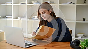 An attractive young Asian female college student making notes on her book