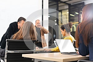 The attractive young Asian girl working on a laptop with group of diverse employees business people team during a brainstorming