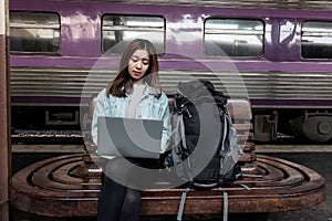 Attractive young Asian lady backpacker using computer laptop for plan to trip. Travel lifestyle concept