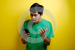 Attractive young asian man reading texting chatting on his phone, bad news, sad crying expression