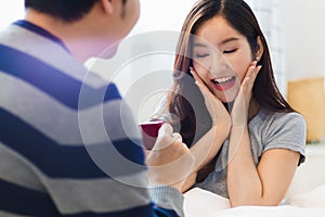Attractive young Asian smile couple man offer wedding ring to happy and excited woman for marriage proposal in romantic moment. Lo