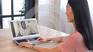 An attractive young Asian woman is using a laptop for video call