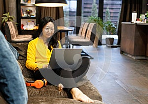 attractive young Asian woman working with laptop on sofa