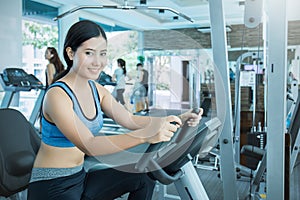 Attractive young asian woman working out with exercise machine at the gym