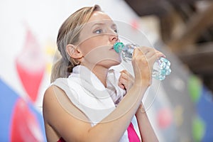 attractive young athlete drinking water in gym