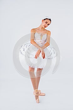 Attractive young ballerina with a beautiful body in leotard dancing tiptoes in photostudio isolated on white background. Showing