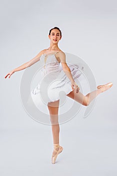 Attractive young ballerina with a beautiful body in leotard dancing tiptoes in photostudio isolated on white background. Showing