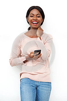 Attractive young black woman laughing with cellphone against white background