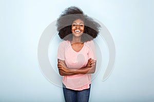 Attractive young black woman smiling with arms crossed against isolated blue background