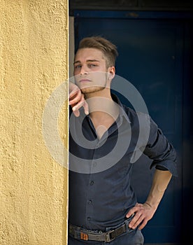 Attractive young blond man leaning against wall