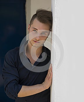 Attractive young blond man leaning against wall