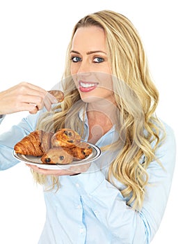 Attractive Young Blonde Haired Woman taking a Danish Pastry From a plate of Assorted Pastries