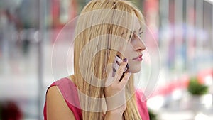 Attractive young blonde lady using smart phone in a city mall
