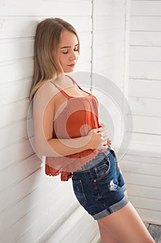 Attractive young blonde woman in red blouse over white wooden background