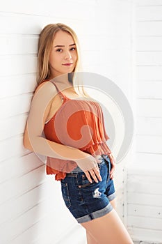 Attractive young blonde woman in red blouse over white wooden background