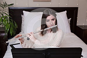 An attractive young brunette caucasian woman playing a clarinet with a music sheet stand in front of her.