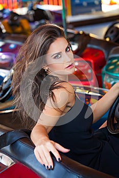 Attractive young brunette caucasian woman portrait in amusement park in car summer day