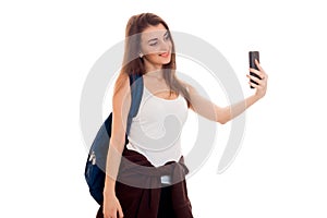 Attractive young brunette students teenager in stylish clothes and backpack on her shoulders posing isolated on white