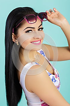 Attractive young brunette woman in pink tank top on blue background. smilling girl in sunglasses