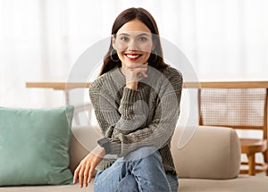 Attractive young brunette woman sitting on couch at home
