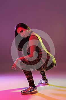 Attractive young brunette woman in the studio dancing Booty dance on a dark background