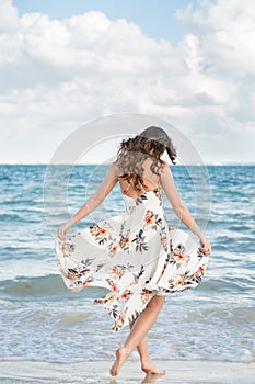 A attractive young brunette woman in a white summer dress on a beach in Mexico.